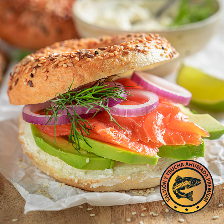 Bagel con salmón ahumado, palta, cebolla morada y eneldo en fondo claro