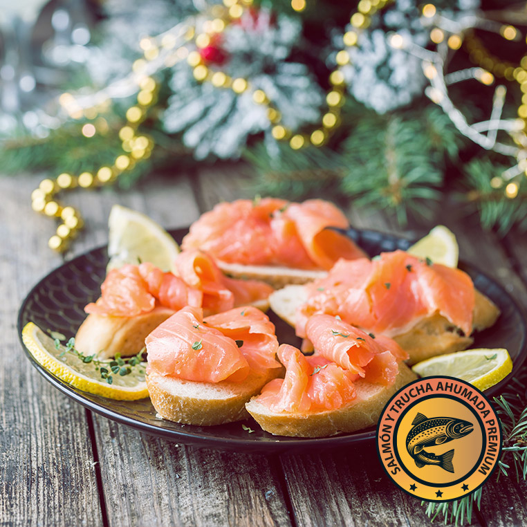Canapés con salmón ahumado artesanal en plato navideño con limón y pan tostado